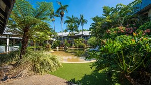 A well-maintained garden with a small pond, palm trees, and a variety of tropical plants. - Cairns Colonial Club Resort (Manunda)