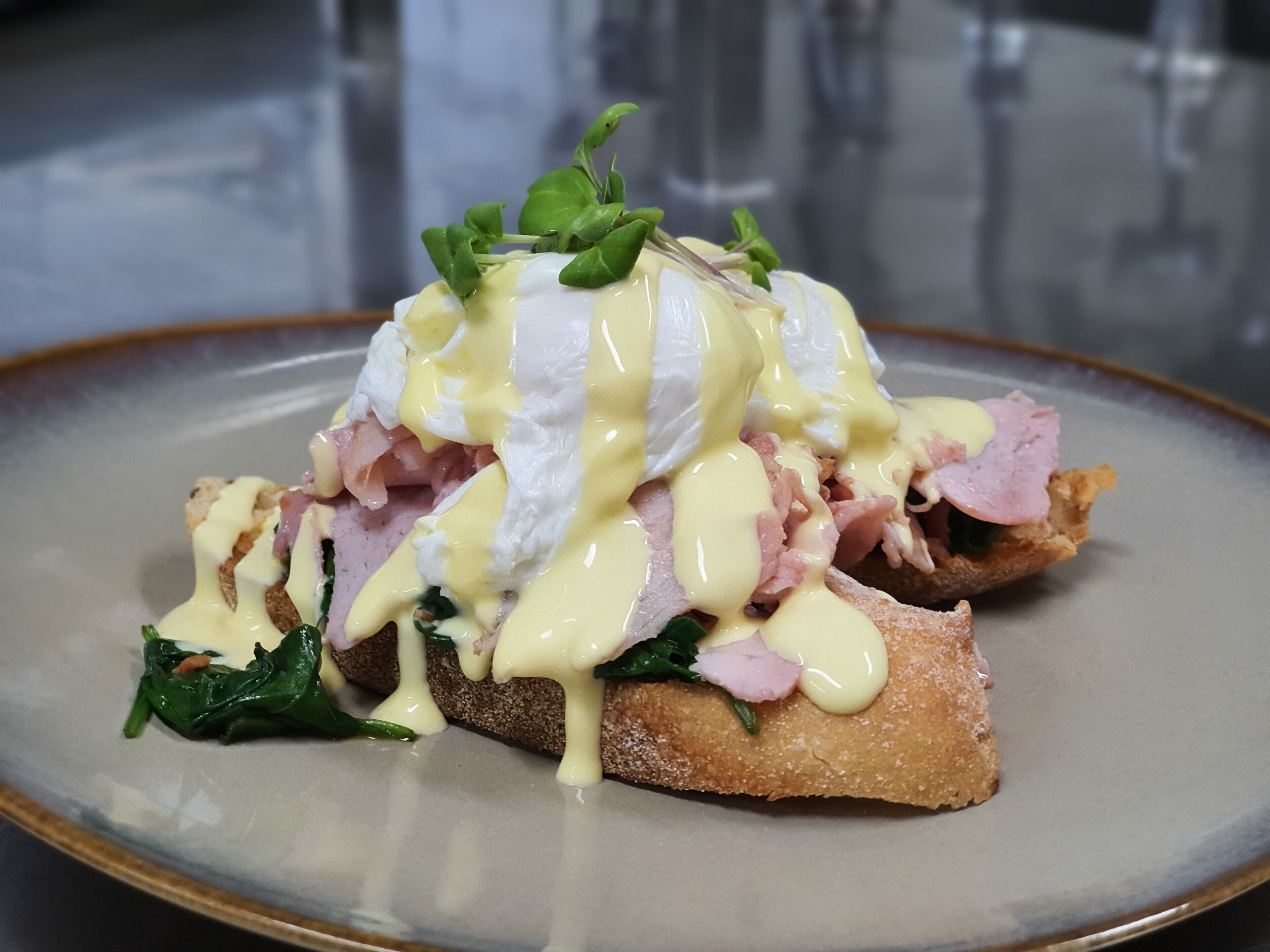 A breakfast dish with poached eggs, ham, and spinach on toast, served on a plate.
