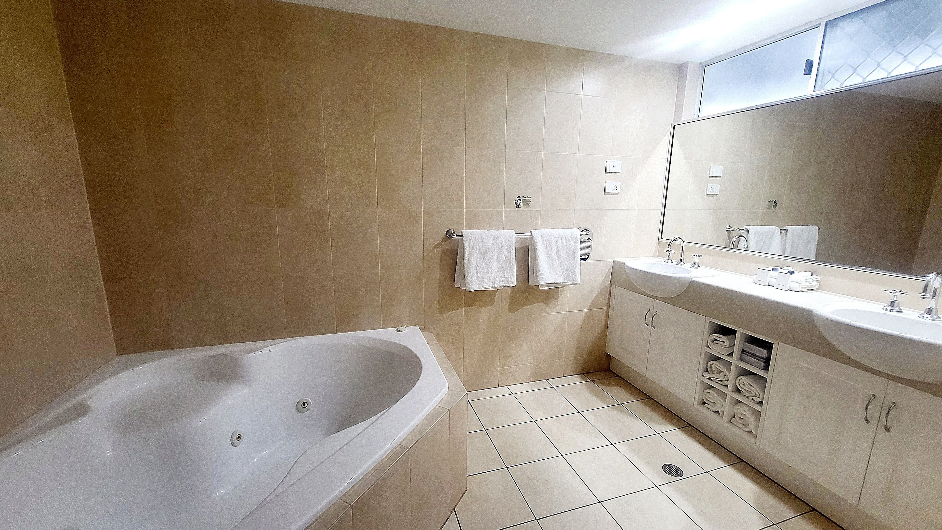 A bathroom with a bathtub, a sink, and a mirror.