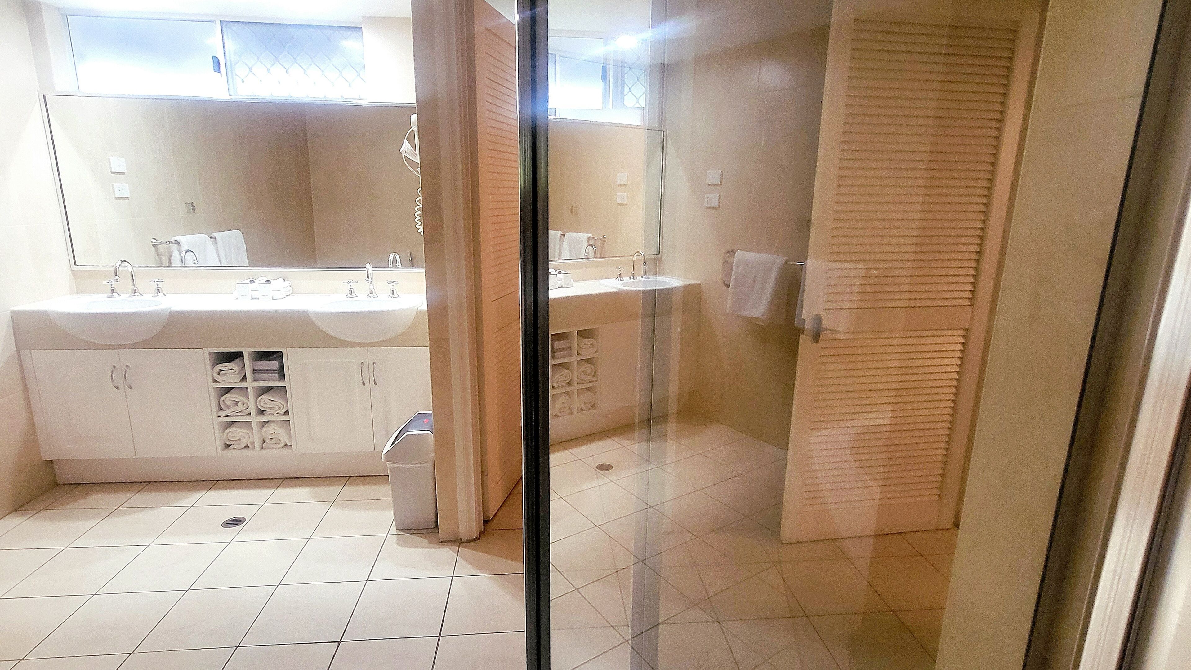 A bathroom with a large mirror, two sinks, and a glass shower enclosure.
