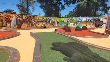 A playground with colorful murals, a sandbox, and a small pond.