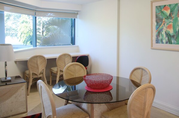 A dining area with a glass table, wicker chairs, and a red bowl.