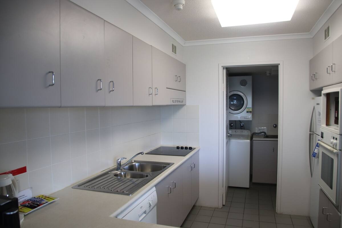 A compact kitchen with a sink, stove, and built-in washer and dryer.