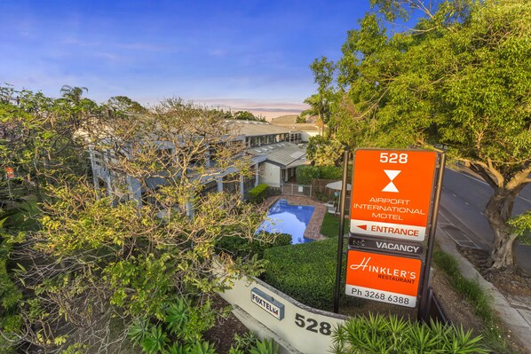 A sign for the 528 Airport International Motel with an entrance arrow, a vacancy sign, and a Hinkler's Restaurant sign. - Airport International Hotel Brisbane (Hamilton)