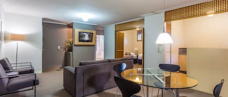 Un salón moderno con mesa de vidrio, sofás oscuros y sillas contemporáneas.
