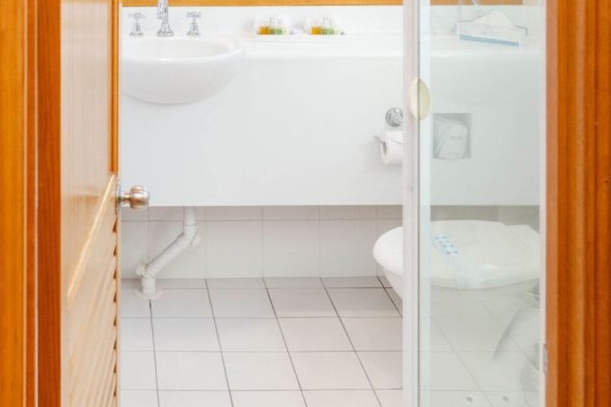 Une salle de bain avec un lavabo blanc, un miroir et des toilettes.