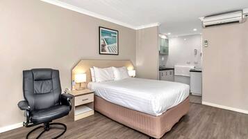 Una camera d'albergo con un letto, una scrivania con una sedia, un angolo cottura e un condizionatore.