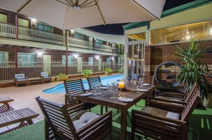 Una piscina al aire libre, sombrillas, sillones reclinables de piscina