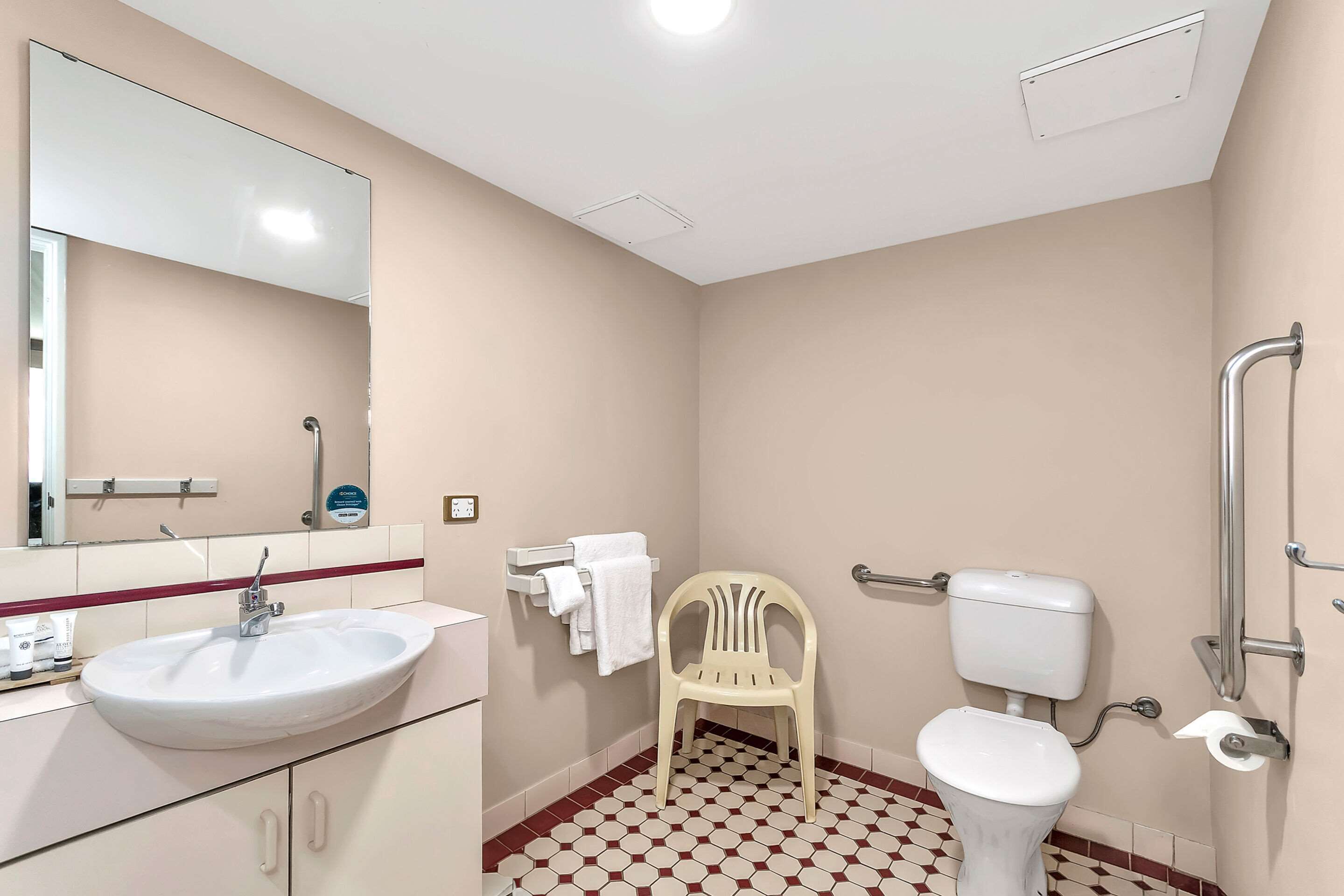 Een badkamer met een wastafel, toilet en een stoel.