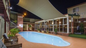 Una piscina interior con toldo, zona de estar y plantas en macetas.