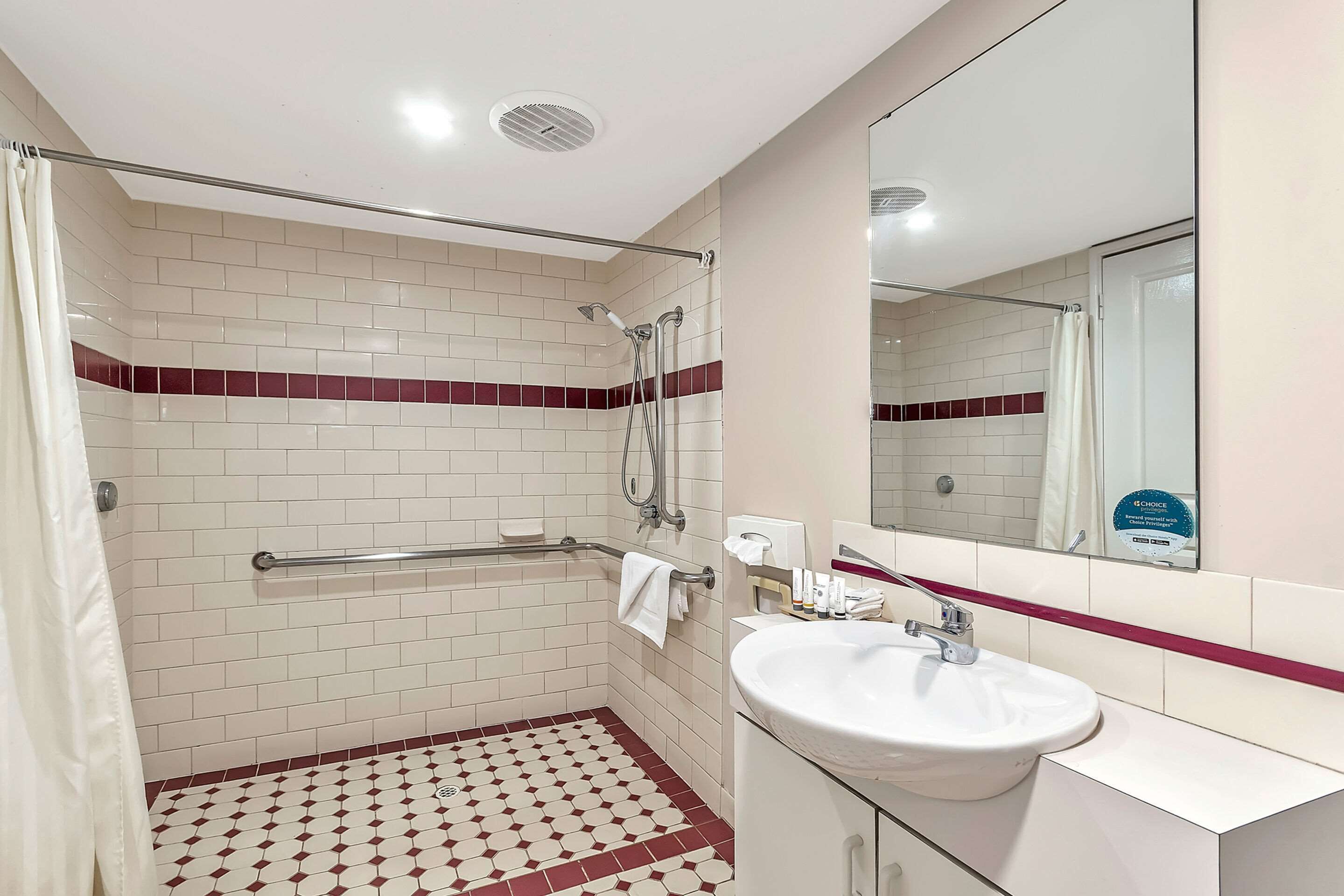 A bathroom with a shower, a sink, and a mirror.