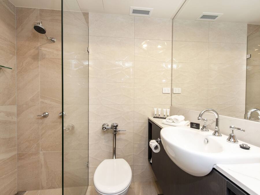 A modern bathroom with a shower, toilet, and dual sinks.