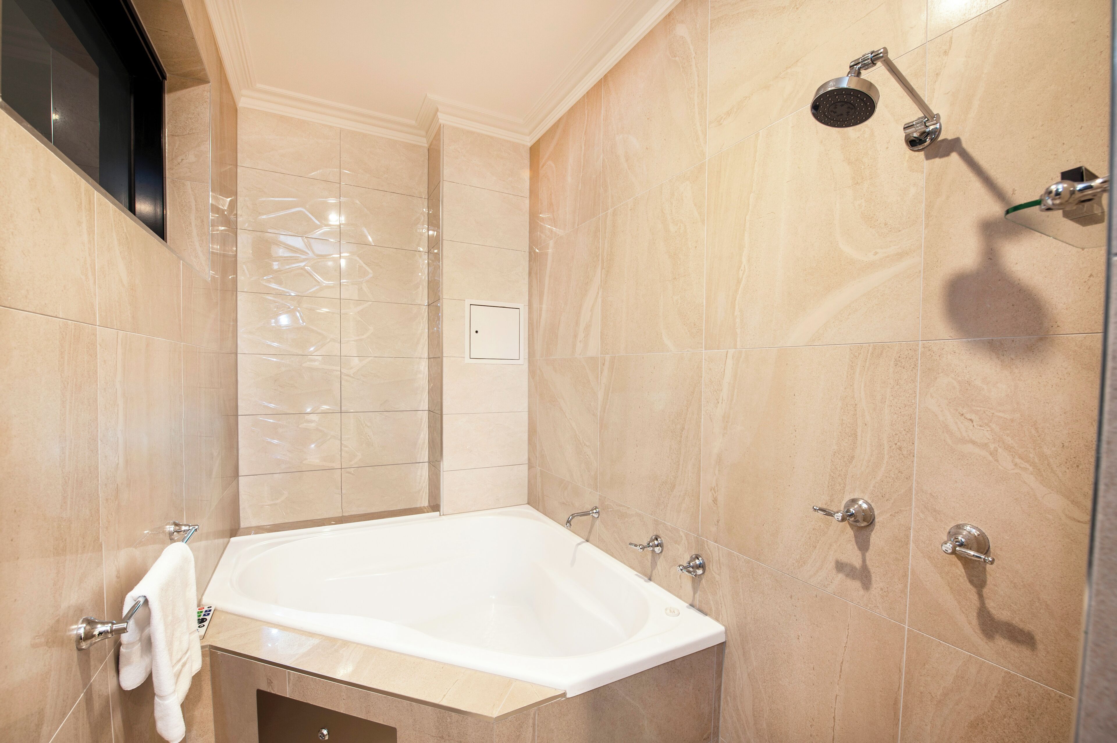 A modern bathroom with a large bathtub, a showerhead, and a towel rack.