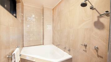 A modern bathroom with a large bathtub, a showerhead, and a towel rack.