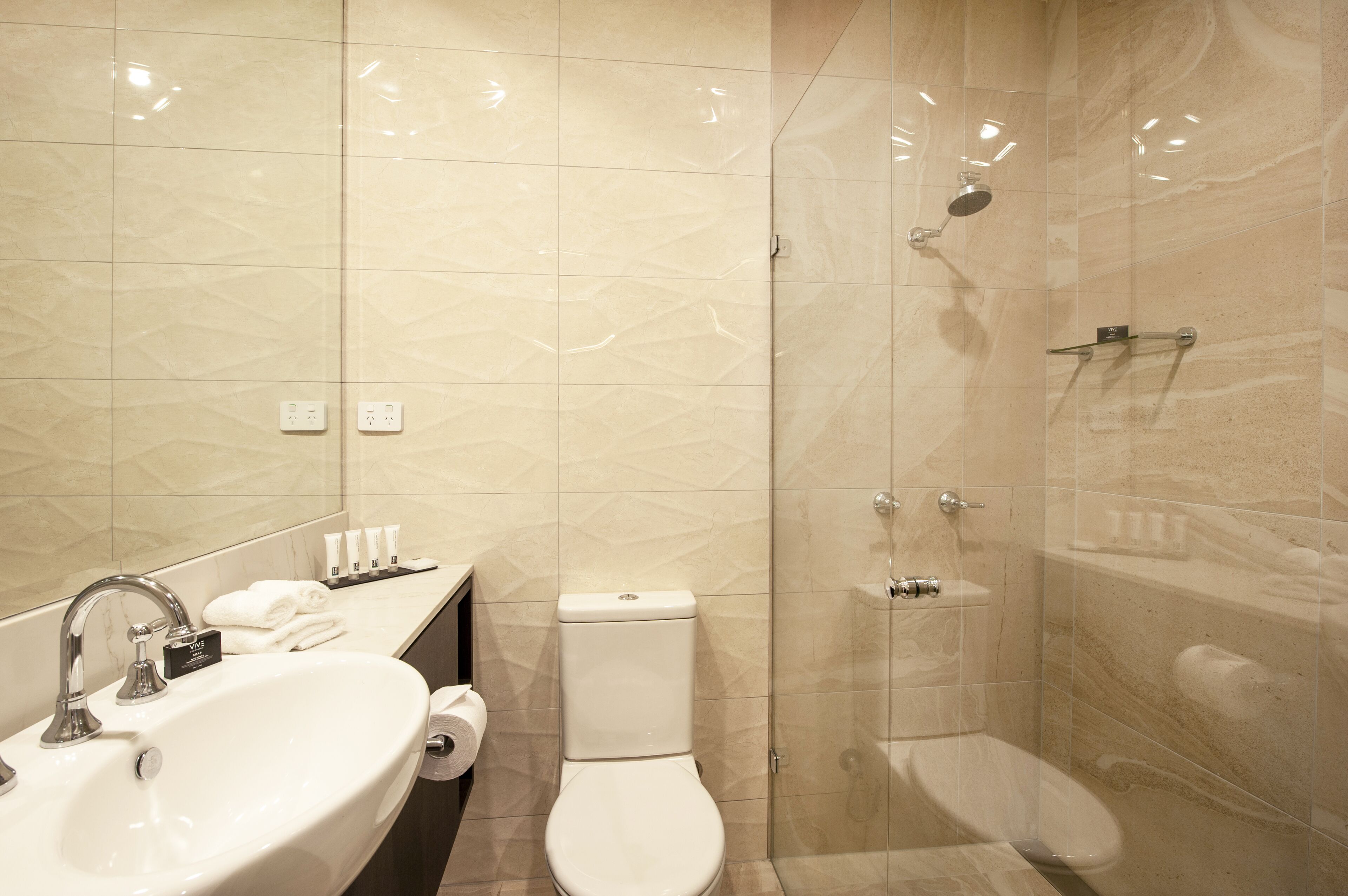 Uma casa de banho moderna com lavatório, sanita e cabine de duche com portas de vidro.
