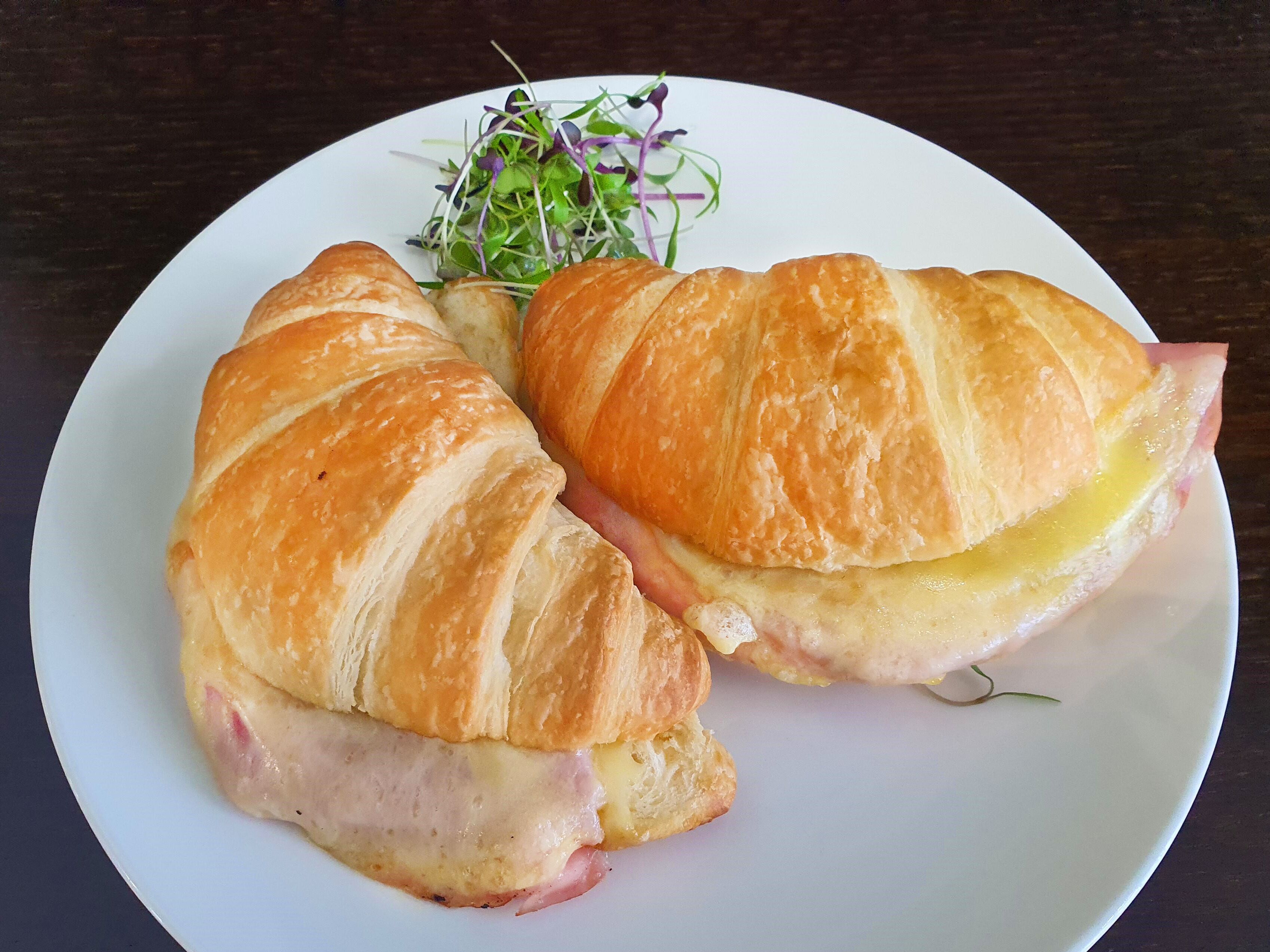 Un plato con dos cruasanes y una ensalada pequeña.