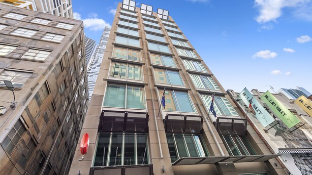A high-rise building with multiple floors, large windows, and a flag. - YEHS Hotel Melbourne CBD (Melbourne)