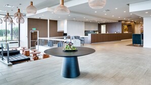 A spacious lobby with a central round table, multiple seating areas, and a reception desk. - Heritage Inn Hotel & Convention Centre Saskatoon (Saskatoon)