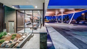 A modern building with a glass facade, outdoor seating area, and a covered parking structure. - Heritage Inn Hotel & Convention Centre Saskatoon (Saskatoon)