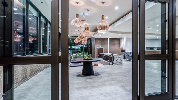 A modern interior with a central round table, glass doors, and pendant lighting. - Heritage Inn Hotel & Convention Centre Saskatoon (Saskatoon)