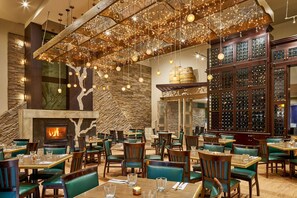 Un restaurant avec un mur en pierre, une cheminée et un meuble à vin.