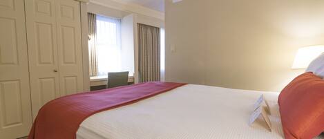Ein Hotelzimmer mit einem großen Bett, einem Schreibtisch und einem Sessel.
