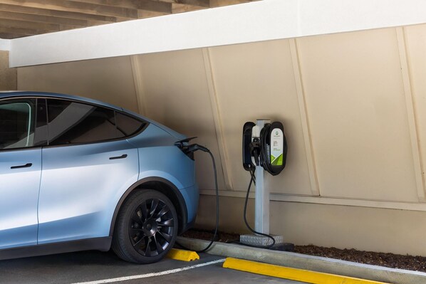 A blue electric vehicle charging at a station.