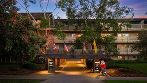 A hotel entrance with a covered walkway, multiple flags, and a mascot statue.