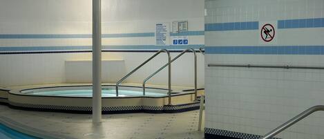 An indoor swimming pool with tiled walls, a no diving sign, and a pool depth marker.