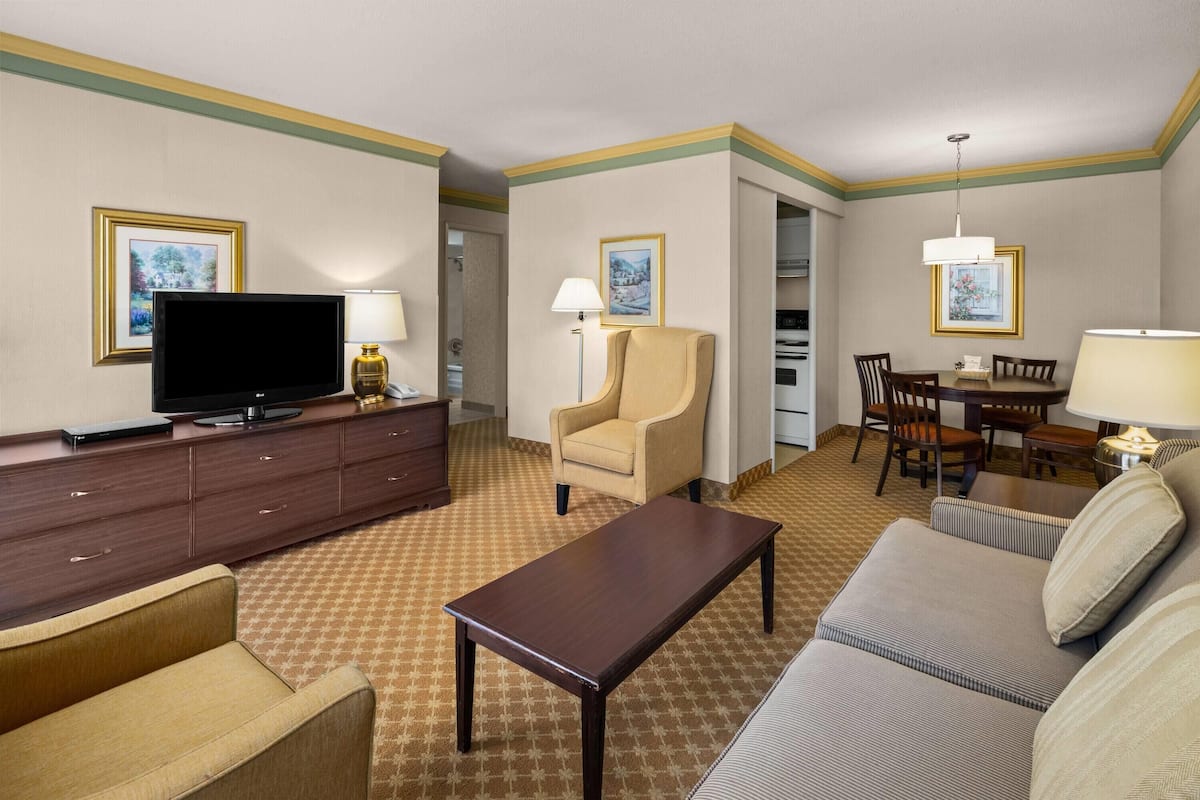 Ett hotellrum med en platt-TV, en soffa, ett matbord och en stol.