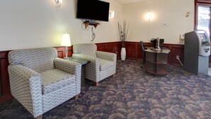 Un hall de hotel con sofá, sillones, televisión y quiosco de autoservicio.