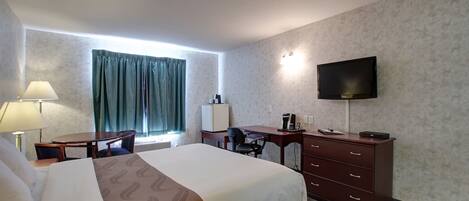 A hotel room with a bed, desk, chair, TV, and a dresser.