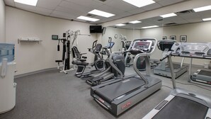 Un gimnasio con cintas de correr, elípticas y máquinas de pesas.