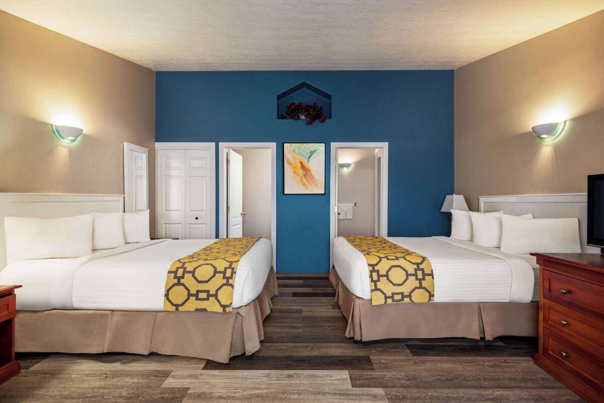 Une chambre d’hôtel avec deux lits, un mur d’accent bleu et un tableau au-dessus de la porte.