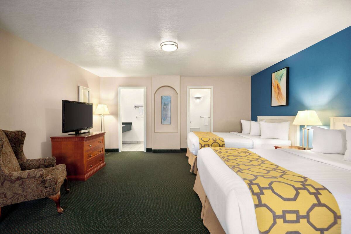 Une chambre d’hôtel avec un lit, une chaise, une télévision et un bureau avec une lampe.
