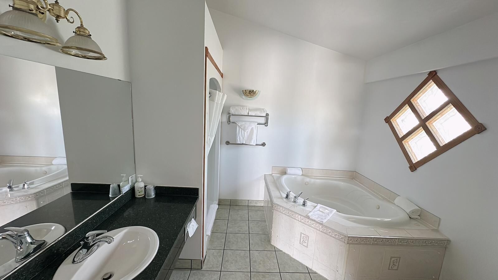 Ein Badezimmer mit zwei Waschbecken, einer Badewanne und einem großen Spiegel.