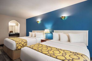 Two single beds with matching headboards and throw blankets, a blue accent wall, and wall-mounted reading lamps.