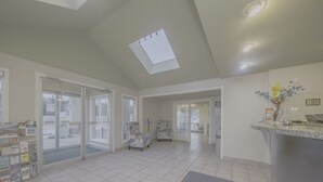 A spacious lobby with a high ceiling, a reception desk, and a large window providing a view outside. - Baymont by Wyndham Hinton (Hinton)