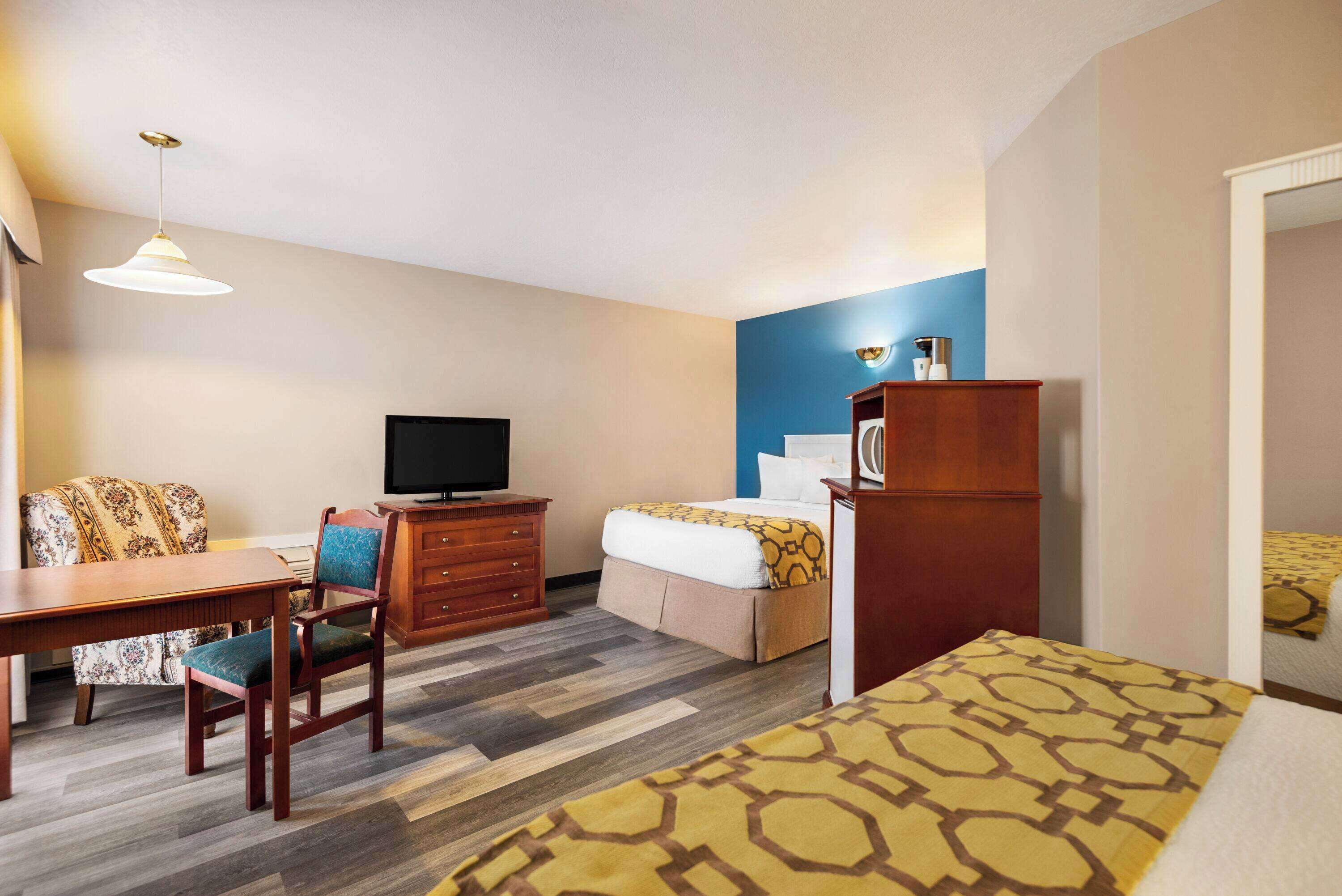 Una habitación de hotel con cama, escritorio, silla, televisor y armario.