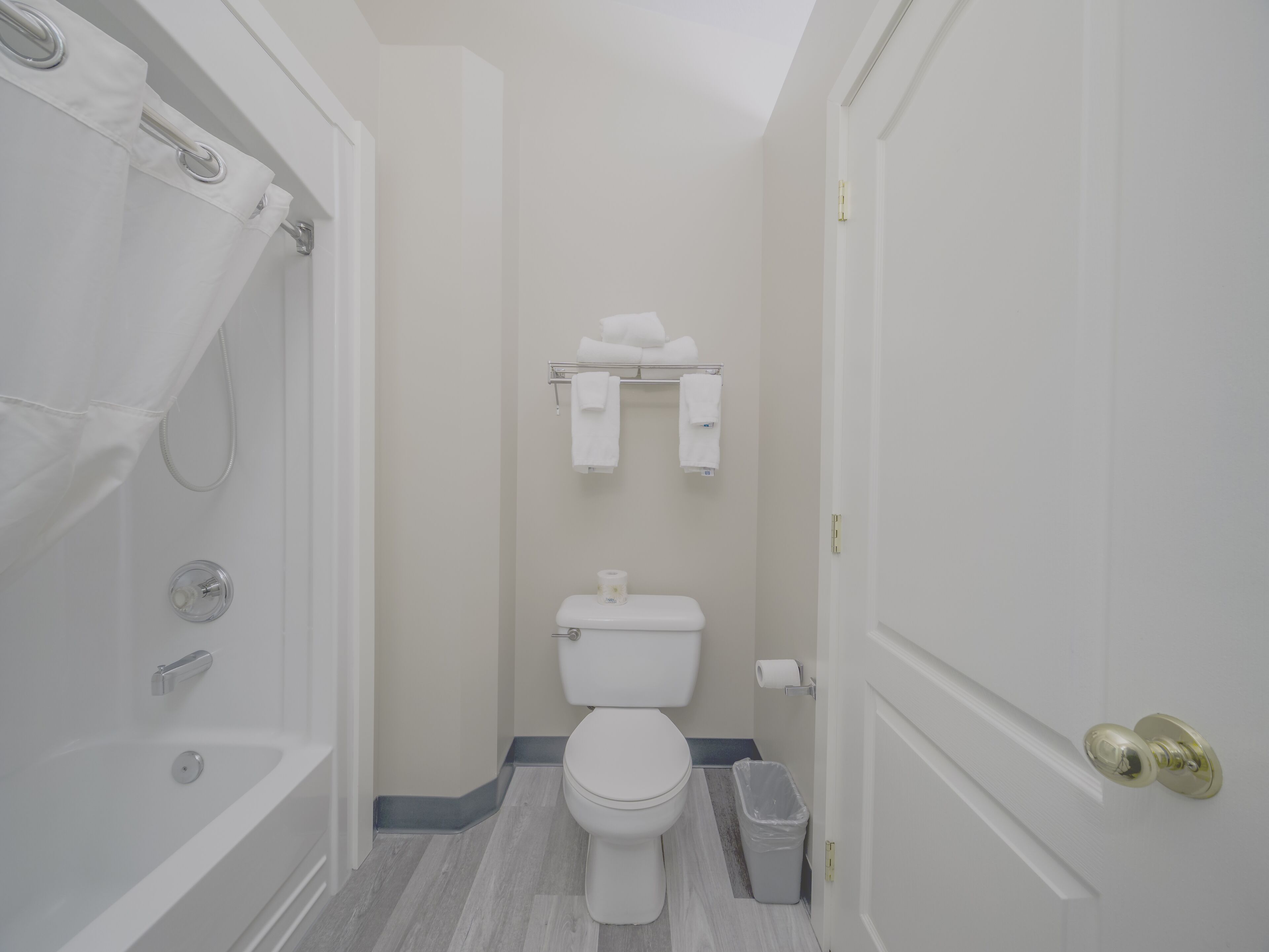A small, clean bathroom with a shower, toilet, and towel rack.
