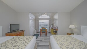 A hotel room with two beds, a television, a desk, a chair, a lamp, and a view of the outside. - Baymont by Wyndham Hinton (Hinton)