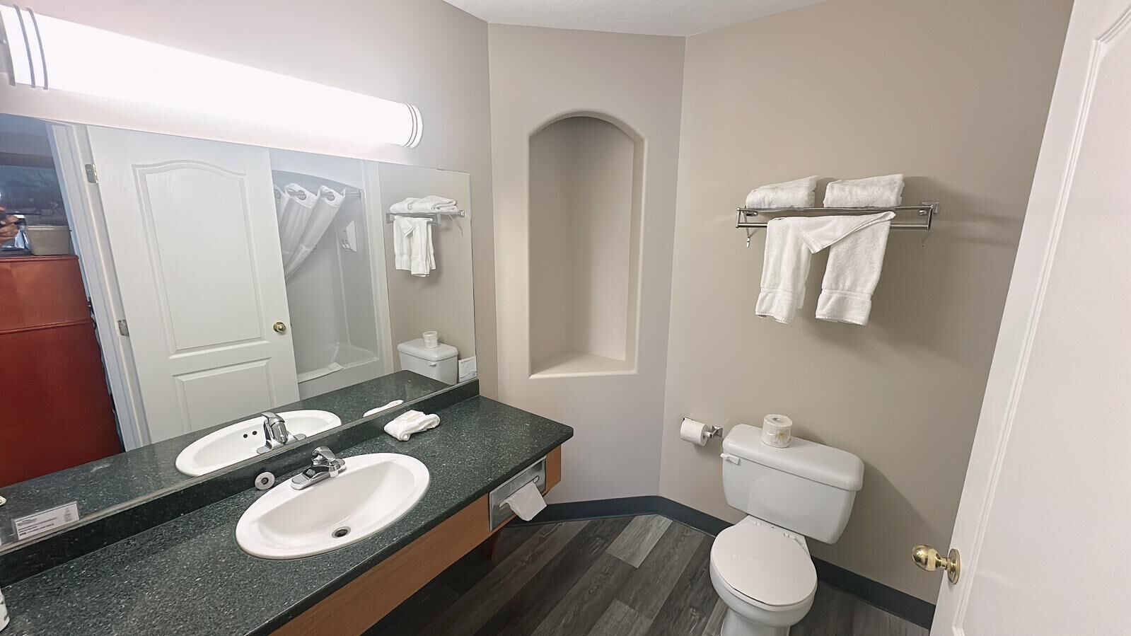 Et badeværelse med to håndvaske, toilet, brusebad og et håndklædestativ.