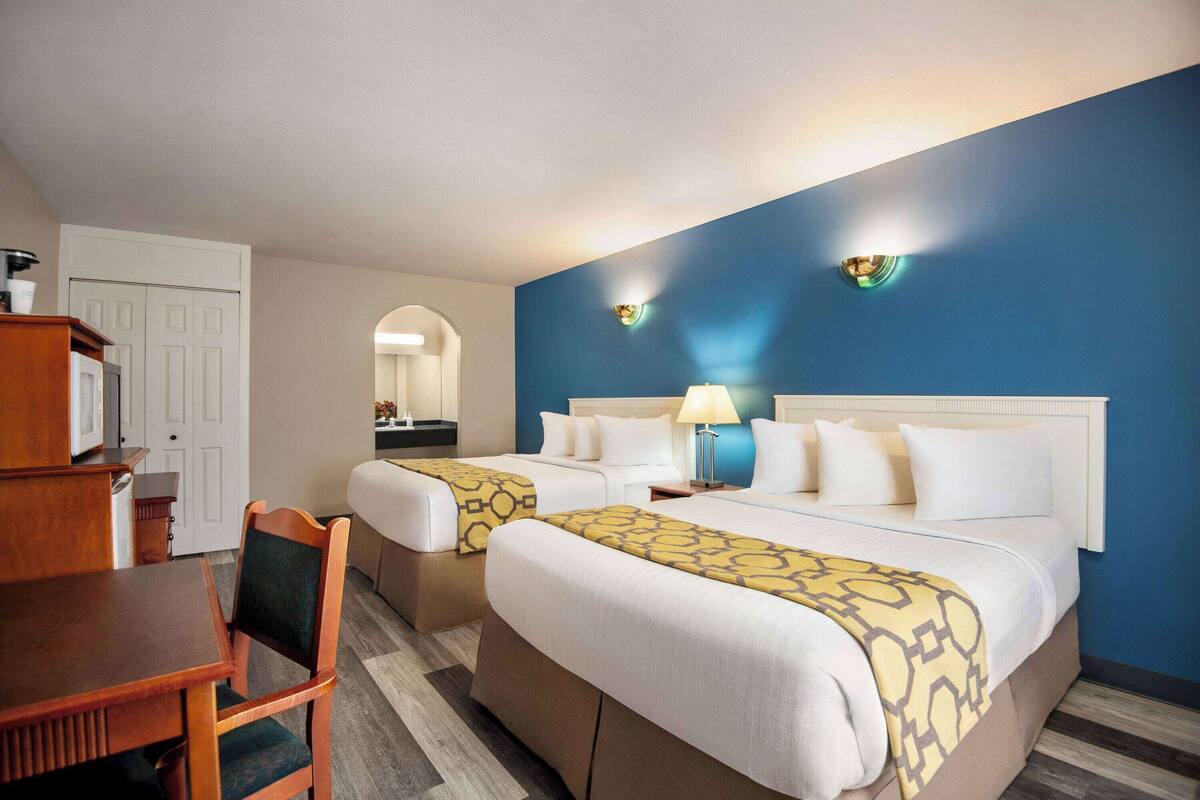Une chambre d’hôtel avec deux lits, une table à manger et un téléviseur.