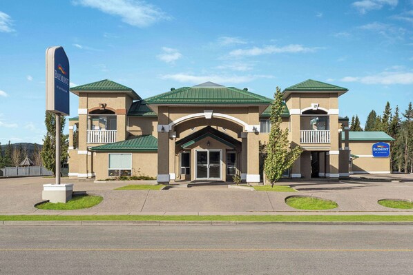 Stunning hotel with a central entrance and two wings, each featuring a balcony with a balustrade.