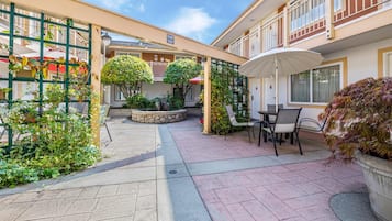 Un patio con zona de estar, plantas en macetas y una mesa cubierta.