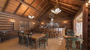 A rustic wooden interior with a high ceiling, wooden dining tables, and chairs.