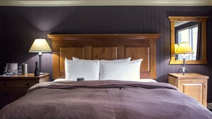 A neatly made bed with a wooden headboard, a bedside table with a lamp, and a mirror on the wall.