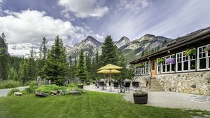 A mountain lodge with outdoor seating and a stone facade.