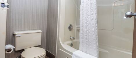 Un baño con inodoro, bañera y cortina de ducha.