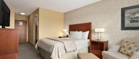 A hotel room with a bed, a desk, a chair, and a television.